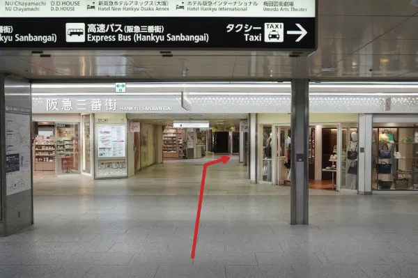 「阪急三番街」の看板と、奥の階段方向を示す赤い矢印